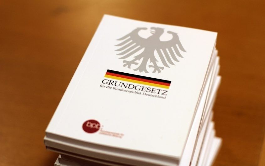 Mehrere Exemplare des Grundgesetzes mit Bundesadler und Deutschlandfarben