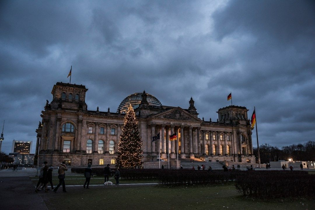 Reichstagsgebäude in Berlin mit beleuchtetem Weihnachtsbaum und Flaggen